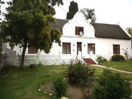De Kleine Post at Mamre &mdash; a whitewashed, thatched Cape Dutch house behind a garden and mature trees.