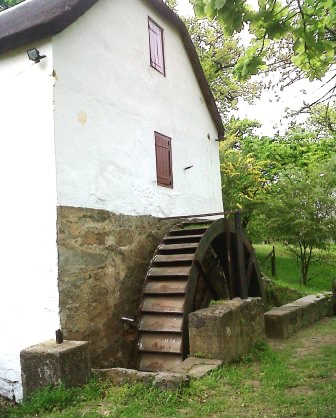 The old watermill at Mamre &mdash; a whitewashed building on a stone base with a large wooden waterwheel against its side.